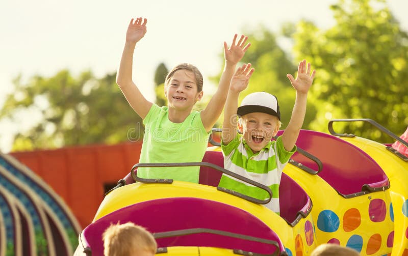 Boy and Girl riding a thrilling roller coaster ride at an amusement park or carnival on a warm summer evening. Boy and Girl riding a thrilling roller coaster ride at an amusement park or carnival on a warm summer evening