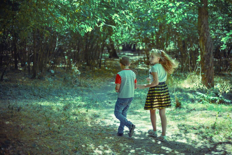 A boy and a girl walk along a path in the forest and look back royalty free stock photography A boy and a girl walk along a path in the forest and look back royalty free stock photography