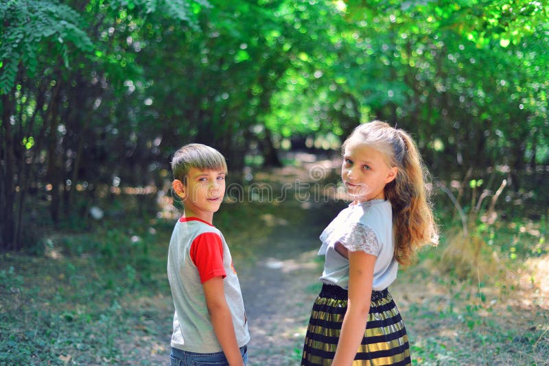 A boy and a girl walk along a path in the forest and look back royalty free stock photo A boy and a girl walk along a path in the forest and look back royalty free stock photo