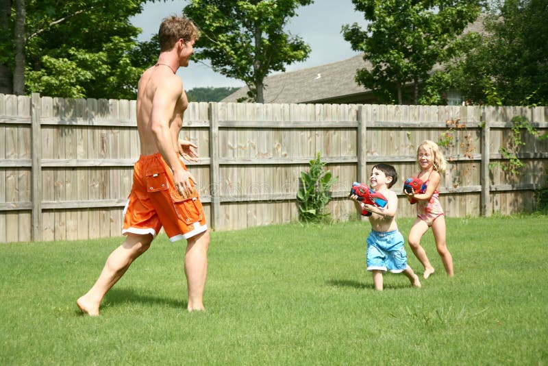 Boy and girl chase dad with waterguns. Boy and girl chase dad with waterguns.