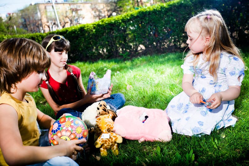 Boy and girls with toys on grass