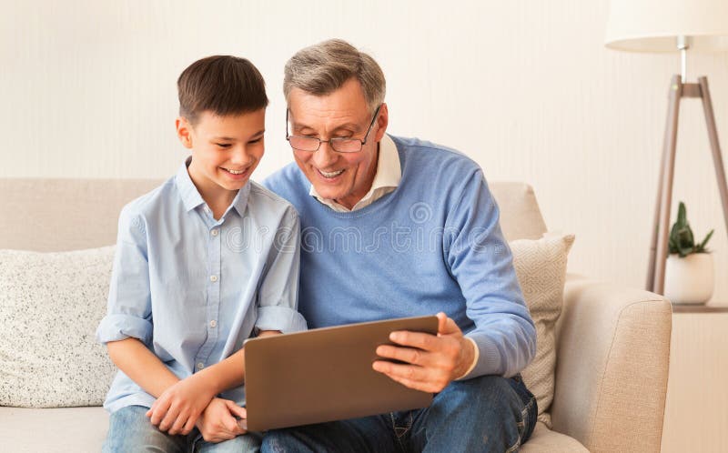 Boy And Grandfather Using Laptop Sitting On Sofa At Home stock photography Boy And Grandfather Using Laptop Sitting On Sofa At Home stock photography