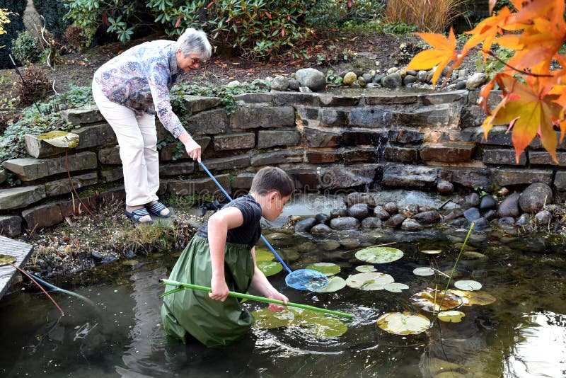 Boy and grandmother cleaning garden pond