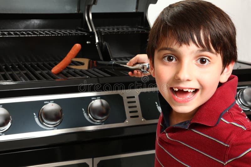 Excited young boy grilling a hotdog and smiling for camers. Excited young boy grilling a hotdog and smiling for camers.