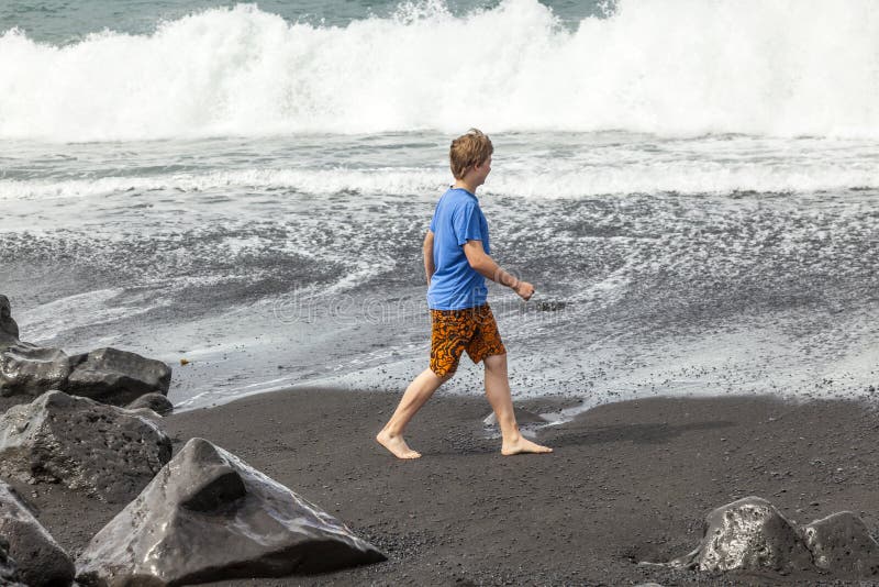 Boy has fun at the black volcanic beach