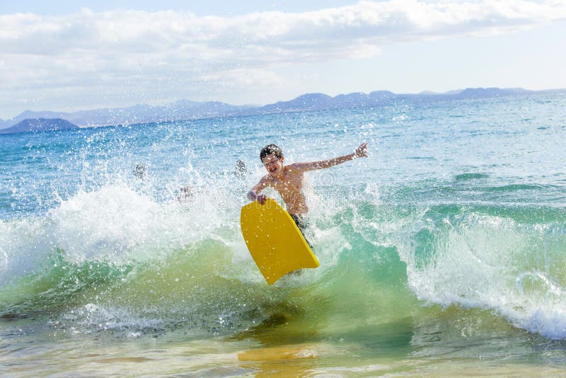 Boy has fun in the ocean with his boogie board