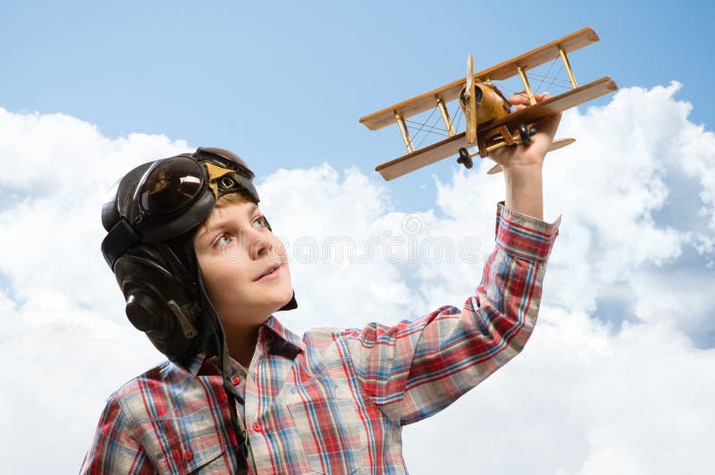 Boy in helmet pilot playing with a toy airplane