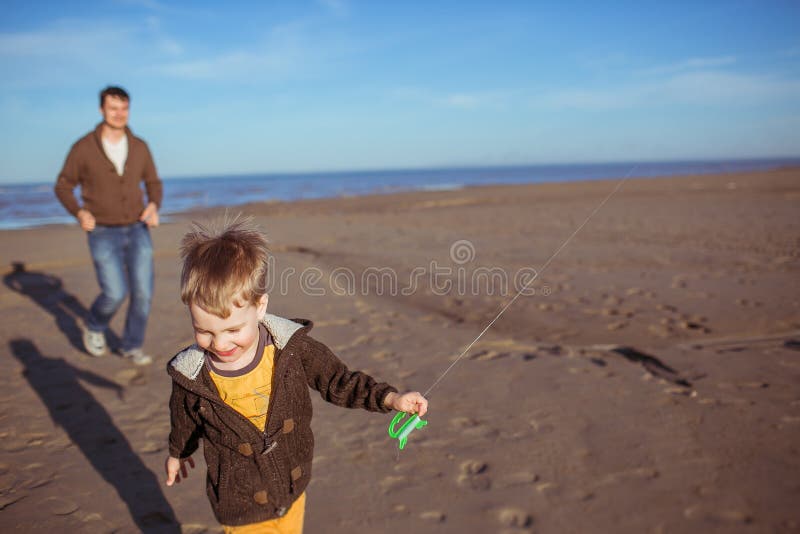 A boy and his dad are running on the sand stock photography A boy and his dad are running on the sand stock photography