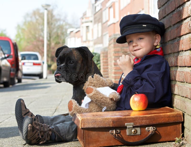 Piccolo ragazzo e il suo cane sulla strada.