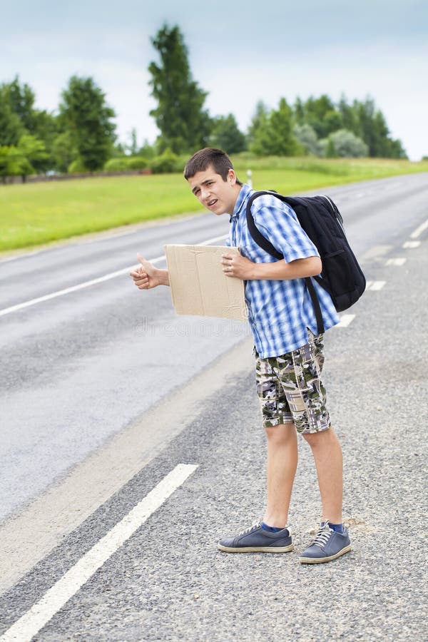 Boy Hitchhiker On The Road Waiting For Car To Stop St