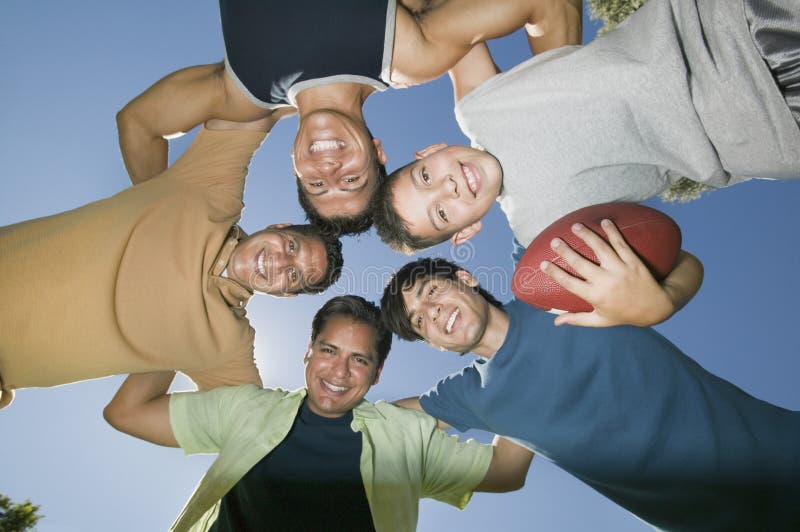 Boy (13-15) holding football with brothers and father in huddle view from below. stock photos Boy (13-15) holding football with brothers and father in huddle view from below. stock photos