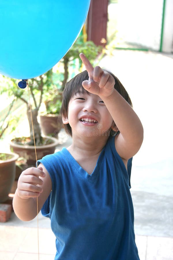 Boy holding & pointing at balloon