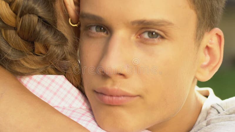 Boy hugging girl and looking at camera, betrayal in relationship, face closeup