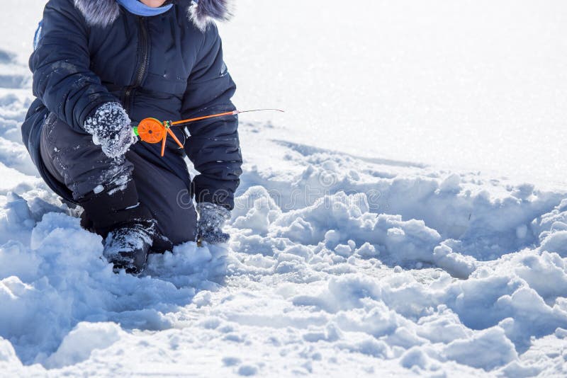 A boy on ice is fishing in the winter stock image