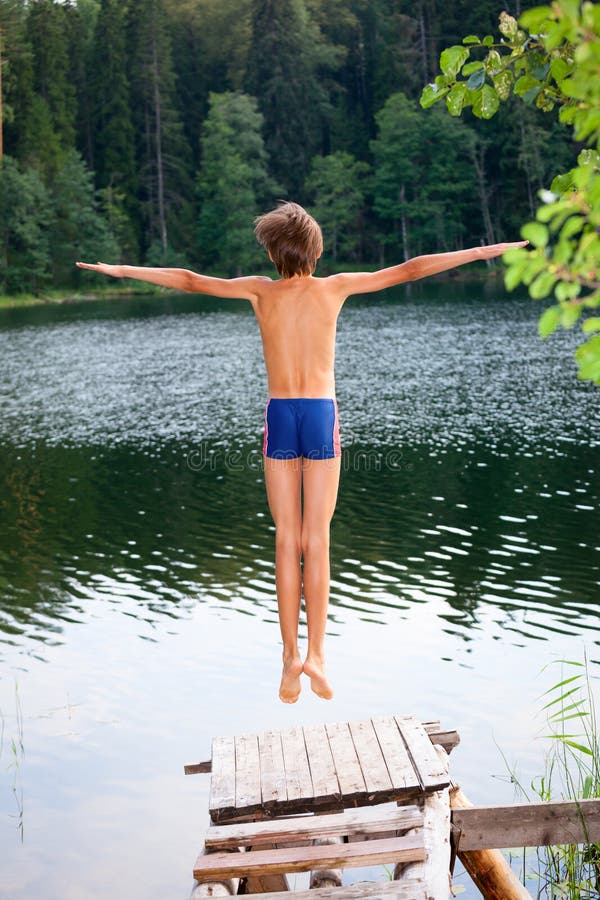 boy jumps in water from tree stock photo - image of
