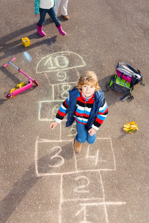 Boy jumping on hopscotch stock image