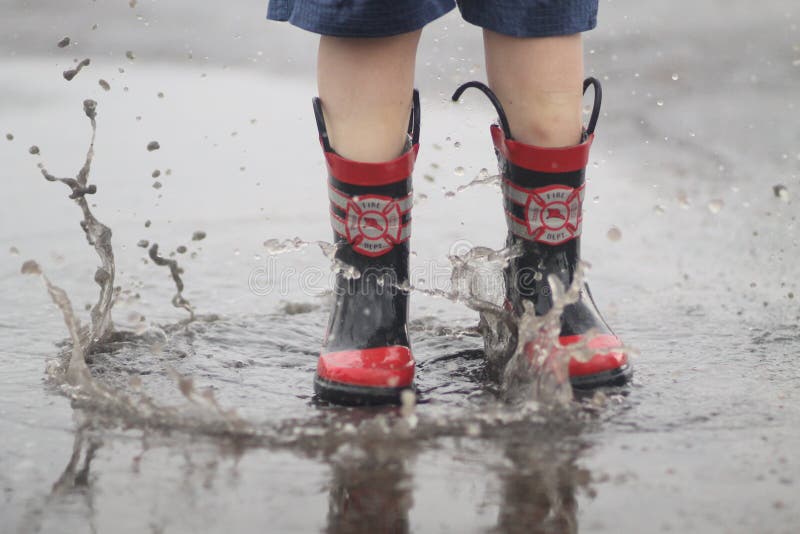 Boy Jumping in Rain Puddle stock photo. Image of water 34582298