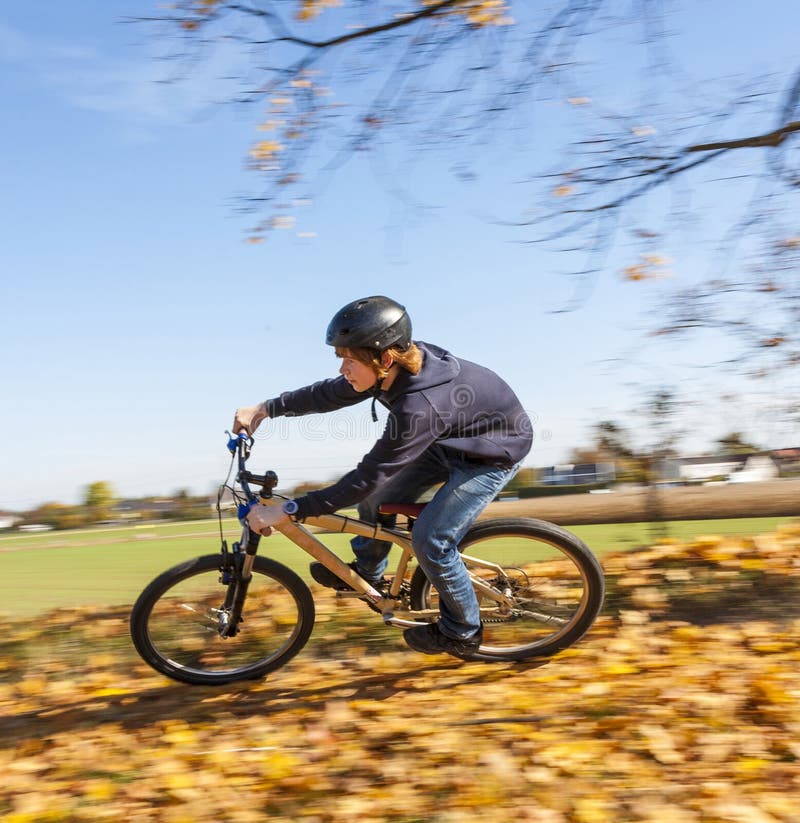 Boy jumps rides his bicycle with speed in open area and enjoys r