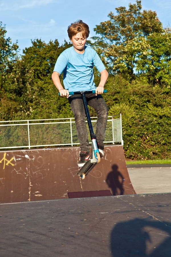 Boy jumps with scooter at the skate park