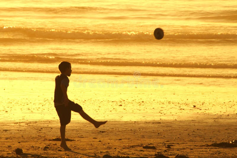 Boy kicking ball on beach