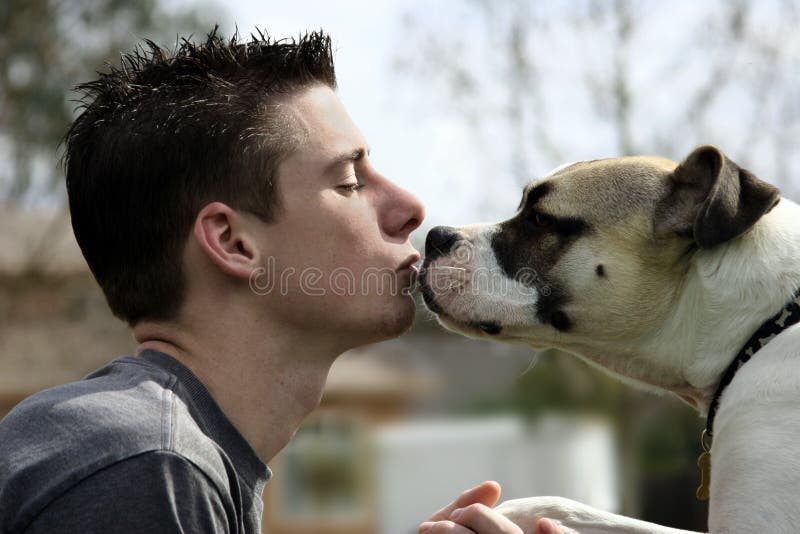 Ragazzo a baciare il suo cane al di fuori.