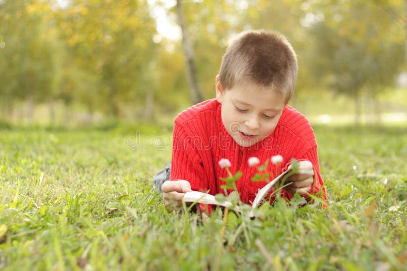 Boy laying on grass and reading
