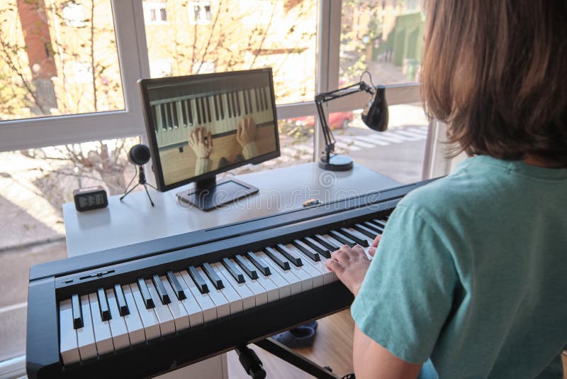 Boy learning to play the piano in distance learning via over the Internet