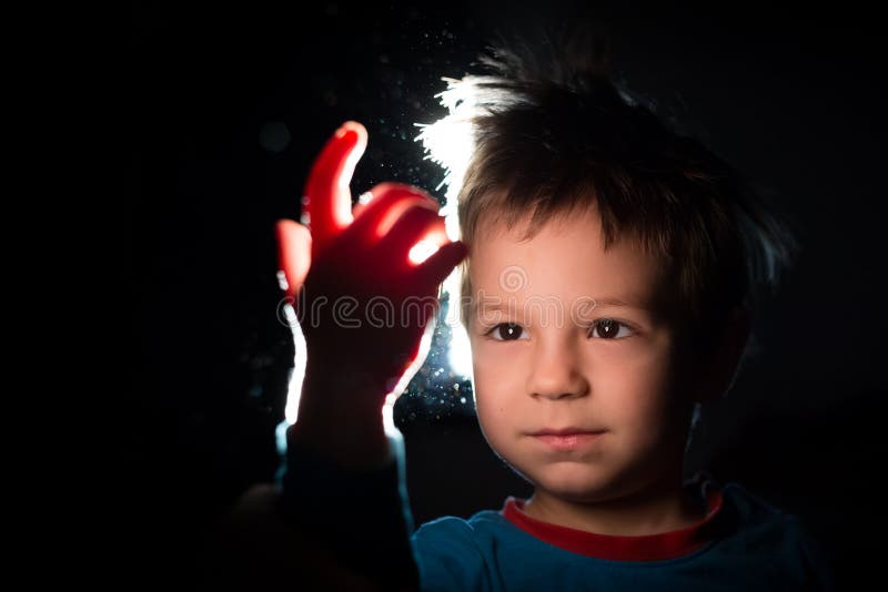 Boy looking with great curiosity at his hand in a ray of light