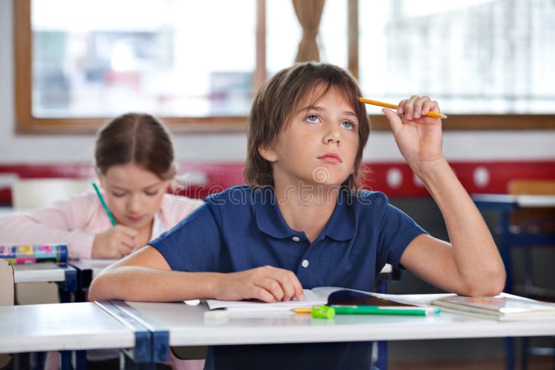 Boy Looking Up While Studying In Classroom