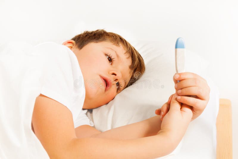 Boy lying in bed and checking thermometer readings