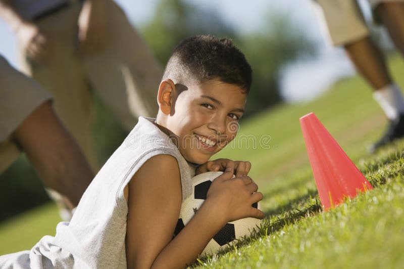 Boy lying down on grass with ball.