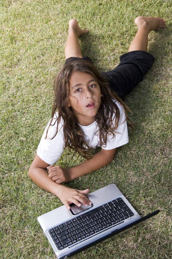 Boy lying on grass with laptop and looking up