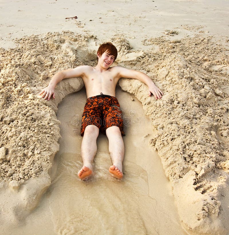 Boy is lying in a sandy bed at the beauti ful beach