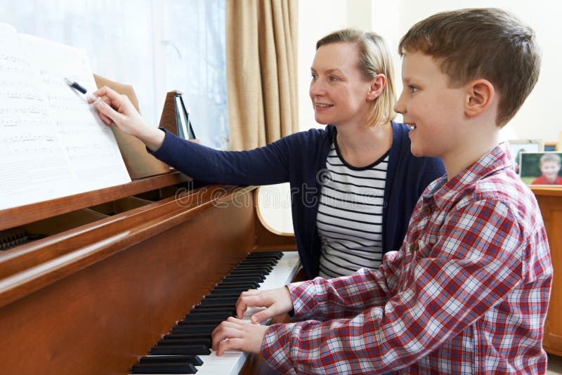 Boy With Music Teacher Having Lesson At Piano