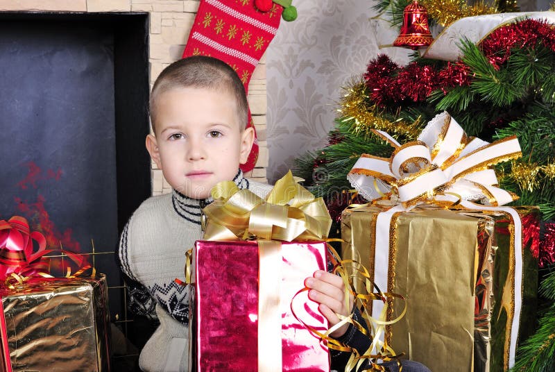 Boy near a Christmas tree with presents