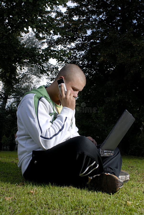 Boy with notebook and cell phone in park