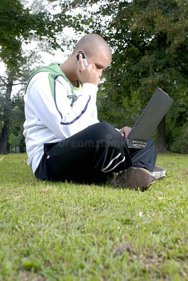 Boy with notebook and cell phone in park