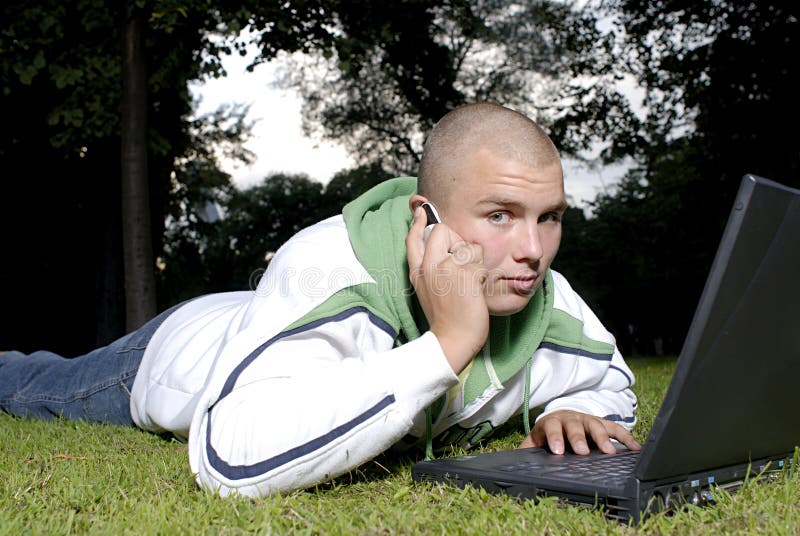 Boy with notebook and cell phone in park