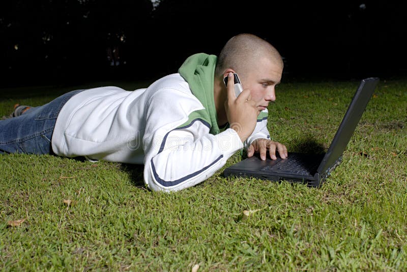 Boy with notebook and cell phone in park