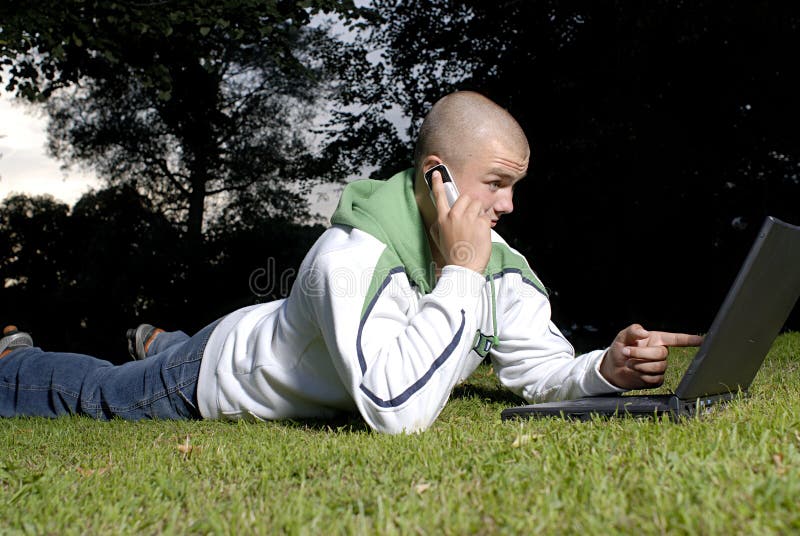 Boy with notebook and cell phone in park