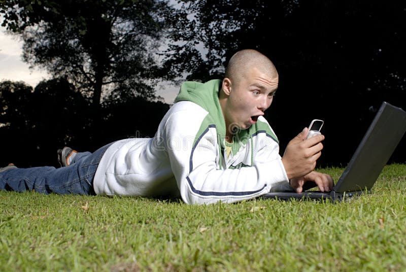 Boy with notebook and cell phone in park