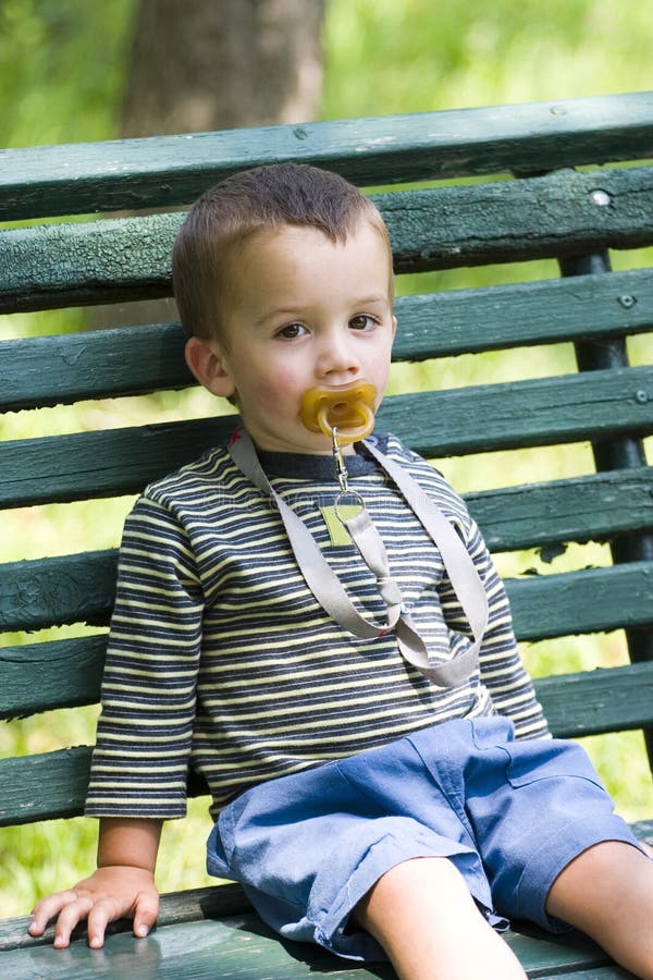 Boy with pacifier on bench stock image. Image of sucking 4491733