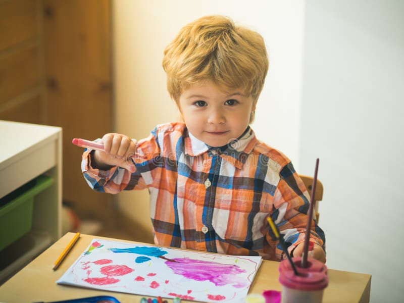 Boy is painting a picture. A beautiful child with felt-tip pens sits at the table and is engaged in creativity and art stock photography Boy is painting a picture. A beautiful child with felt-tip pens sits at the table and is engaged in creativity and art stock photography