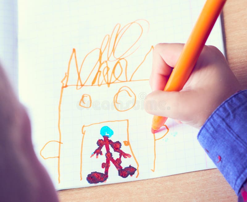 Boy is painting a picture. A beautiful child with felt-tip pens sits at the table and is engaged in creativity and art