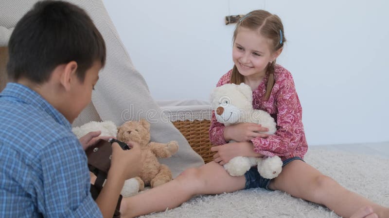 Boy photographing little girl with retro camera