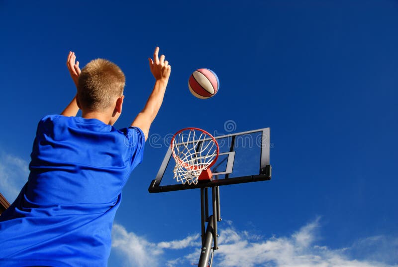 Chlapec basketbal mimo s modrou oblohou v pozadí.