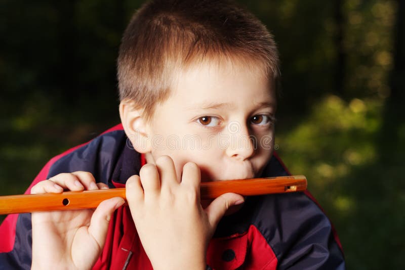 Boy playing flute in dark forest royalty free stock photography