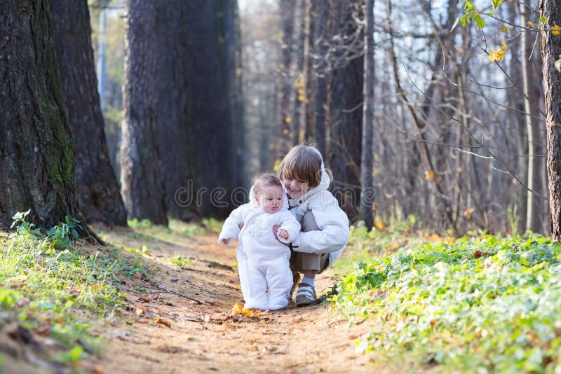 Boy playing with his baby sister in the park stock photo Boy playing with his baby sister in the park stock photo
