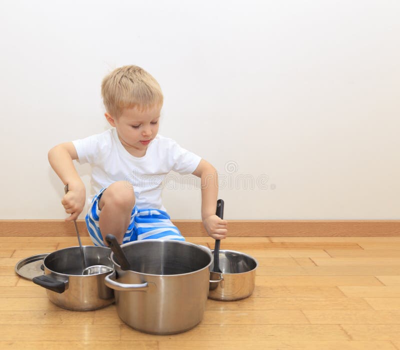 Baby boy playing on kitchen counter with strainer over his head Stock Photo