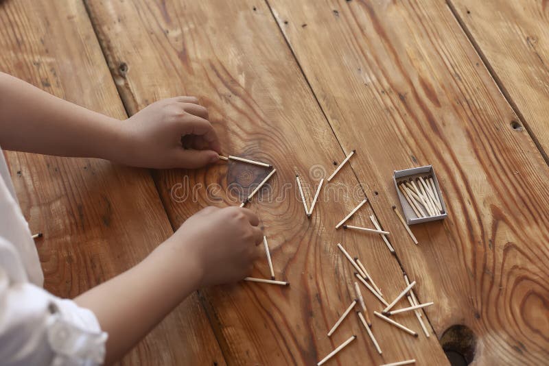 A boy playing with matchsticks. Young kid plays match sticks on wooden background
